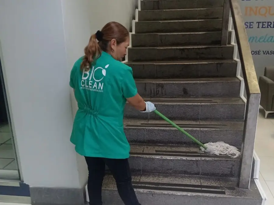 Colaboradora de BioClean limpiando escaleras en un edificio de oficinas en Puebla